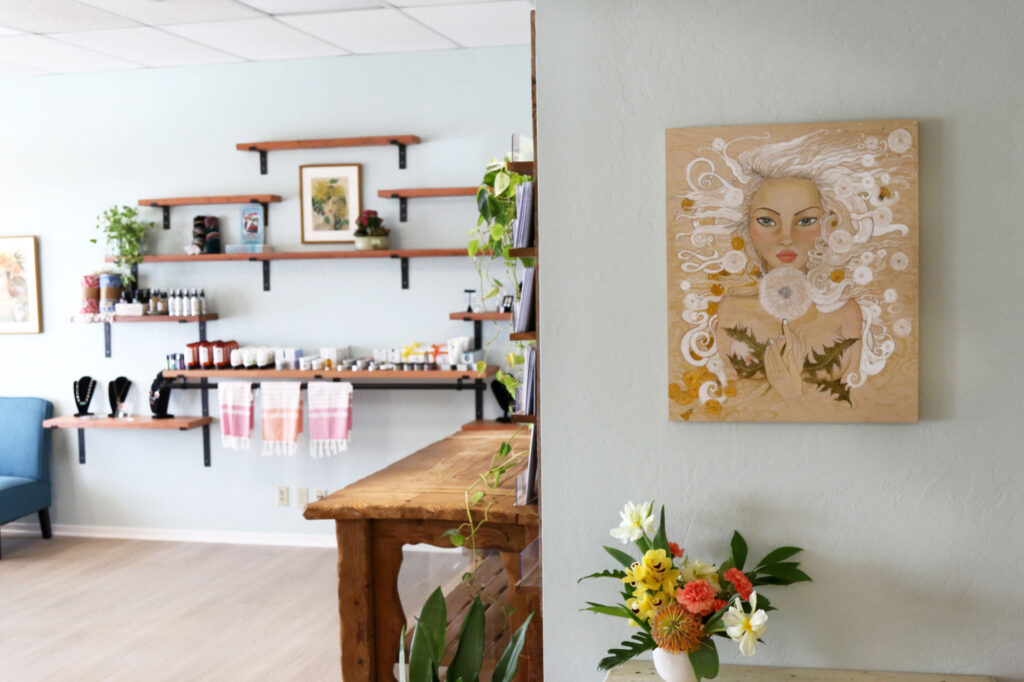 Studio shelves with wellness goods beside local artwork